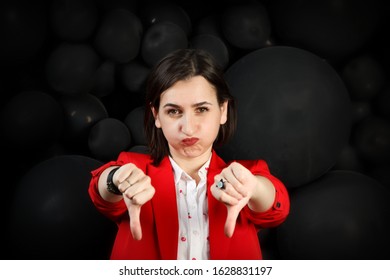 Young woman with a sad face extended her arms with thumbs down. Everything is bad. girl pouting lips in difficult circumstances. Woman in red on black bubble background. Copy space - Shutterstock ID 1628831197