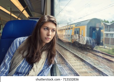 The Young Woman Sadly Looking Out The Window Sitting Inside The Train Car.