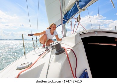 Young Woman Sailing On A Yacht. Female Sailboat Crewmember Trimming Main Sail During Sail On Vacation In Summer Season