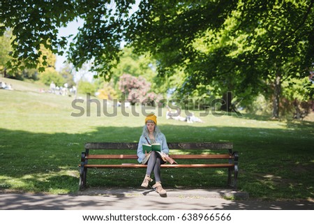 Young woman sat reading her book in the park