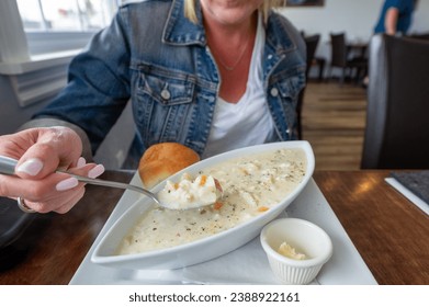 Young woman savoring a spoonful of delicious seafood chowder in Nova Scotia. - Powered by Shutterstock