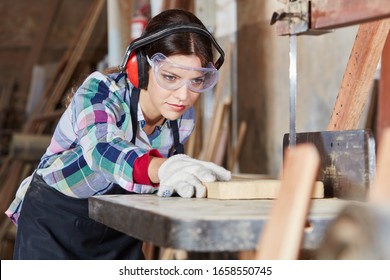 Young woman sawing wood during her apprenticeship in a joinery