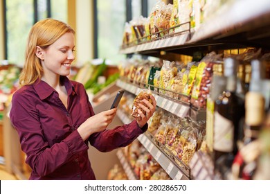 Mujer joven escaneando el código de barras de una bolsa de nueces en un supermercado con su smartphone