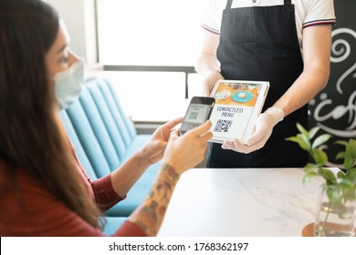 Young Woman Scanning QR Code Of Contactless Menu Through Smartphone In Restaurant
