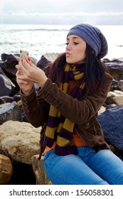 Young Woman With Scarf And Hat Taking Picture Of Herself With Iphone