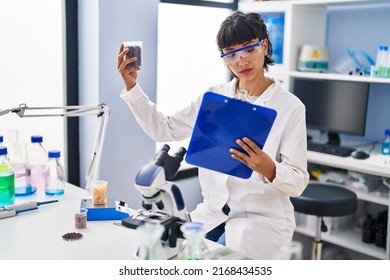 Young Woman Scientist Holding Clipboard And Sample At Laboratory