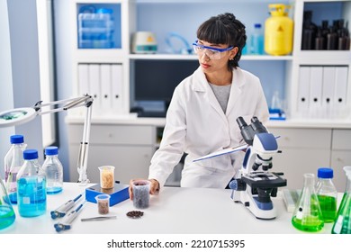 Young Woman Scientist Holding Clipboard And Sample At Laboratory