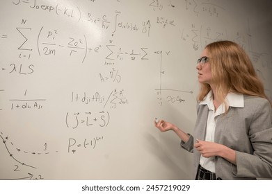 Young woman scientist writes formulas on a white board.  - Powered by Shutterstock