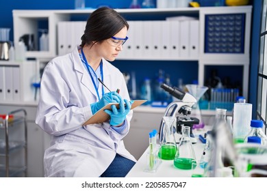 Young Woman Scientist Writing On Notebook At Laboratory