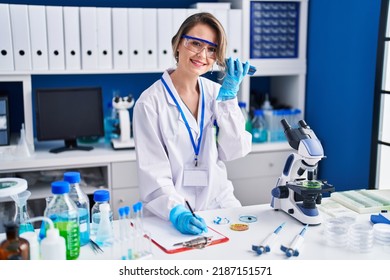 Young Woman Scientist Writing Report Listening Audio Message At Laboratory