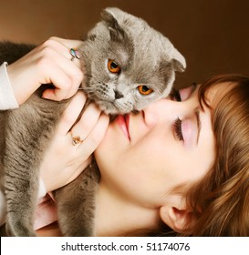 Young woman with scottish-fold cat.On brown background.