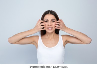 Young Woman Scratching Face On Light Background. Annoying Itch