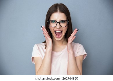 Young woman screaming over gray background
