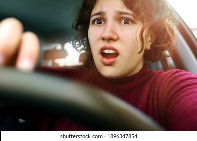 Young Woman Screams In Fear At Wheel Of Car. Curly Girl Driver Is Panicked And Very Scared Of Accident.