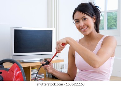 Young Woman With Screwdriver And Plug By Hoover And Computer Screen, Smiling, Portrait