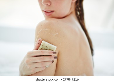 Young Woman Scrubbing Her Shoulder With Soap Bar In Bath