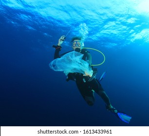 Young Woman Scuba Diver Picks Up Plastic Trash From Ocean. Beach Cleanup Concept 