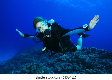 Young Woman Scuba Diving On A Beautiful Coral Reef