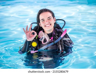 Young woman with scuba gear on in a pool smiling at the camera showing the OK sign - Powered by Shutterstock