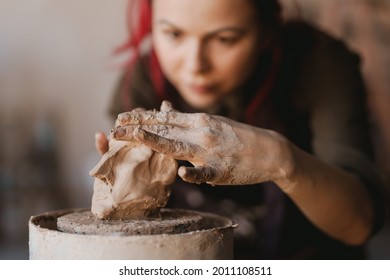 Young woman sculptor artist creating a bust sculpture with clay in an art studio close up