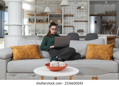 Young Woman Search The Internet On Laptop Computer Ads For Selling And Buying Cars. Woman Searches The Internet In Search Of A Reliable And Affordable Moving Company. 