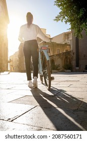 Young Woman Seen From Behind Takes A Bike Ride In An City Break Sunny Day