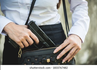 Young woman self defence putting gun in her small handbag