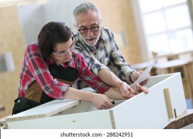 Young Woman With Senior Craftsman In Carpentry Class