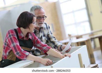 Young Woman With Senior Craftsman In Carpentry Class