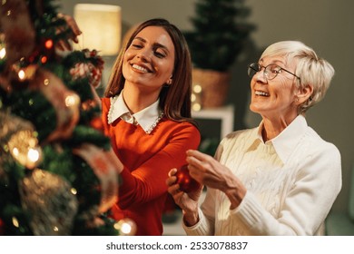 Young woman and a senior woman are decorating a christmas tree in a warm and cozy living room, enjoying their time together during the holiday season - Powered by Shutterstock