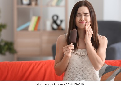 Young Woman With Sensitive Teeth And Cold Ice Cream On Sofa At Home