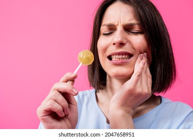 Young Woman With Sensitive Teeth Eating Sweet Lollipop On Color Background