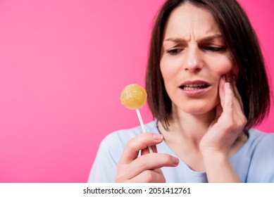 Young Woman With Sensitive Teeth Eating Sweet Lollipop On Color Background