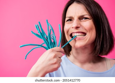 Young Woman With Sensitive Teeth Eating Sweet Candies On Color Background