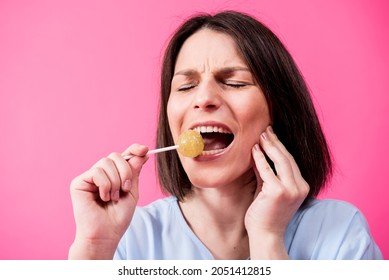 Young Woman With Sensitive Teeth Eating Sweet Lollipop On Color Background