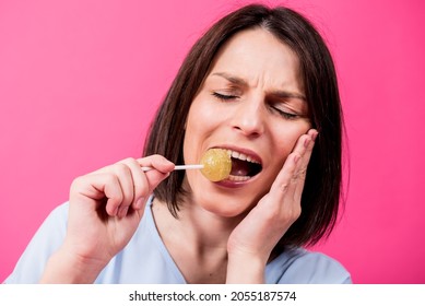 Young Woman With Sensitive Teeth Eating Sweet Lollipop On Color Background