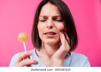 Young Woman With Sensitive Teeth Eating Sweet Lollipop On Color Background