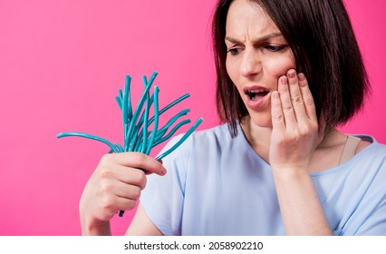 Young Woman With Sensitive Teeth Eating Sweet Candies On Color Background