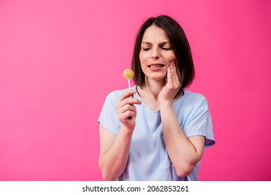 Young Woman With Sensitive Teeth Eating Sweet Lollipop On Color Background