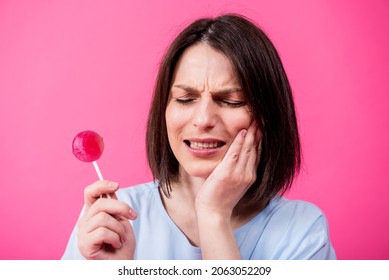 Young Woman With Sensitive Teeth Eating Sweet Lollipop On Color Background