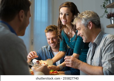 Young Woman Serving Plate Of Cheese To Man In Kitchen
