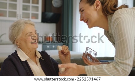 Young woman serving turkish delight to her mother to traditionally celebrate Eid al-Fitr (candy feast) after the end of the blessed month of Ramadan.