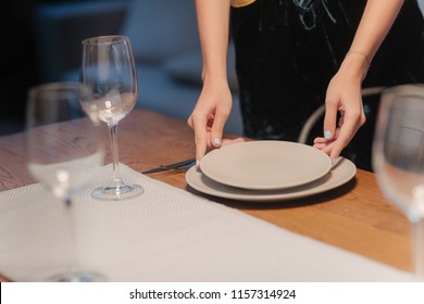 Young Woman Setting Up Table For Dinner Party At Home.