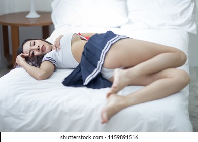 young woman in sexy japanese anime cosplay, japanese school uniform cosplay, posing in bed.