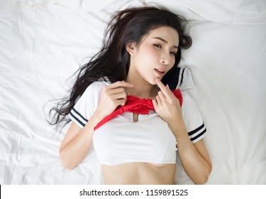 young woman in sexy japanese anime cosplay, japanese school uniform cosplay, posing in bed.