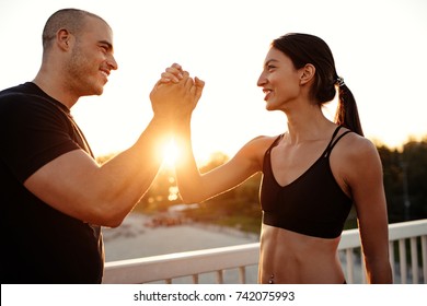 A young woman is shaking the arm of her personal trainer.