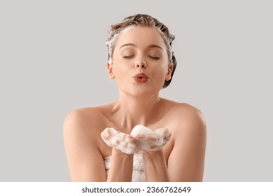 Young woman with shampoo blowing kiss on light background - Shutterstock ID 2366762649