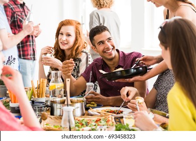 Young woman shares bio and fresh meal with her friend during dinner in home - Powered by Shutterstock