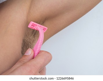 Young woman shaves hairy armpits. Female unshaved armpits, depilation, hair removal concept. Close-up, selective focus.