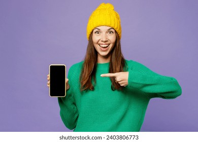 Young woman she wearing green sweater yellow hat casual clothes hold in hand use point on mobile cell phone with blank screen area isolated on plain pastel light purple background. Lifestyle concept - Powered by Shutterstock